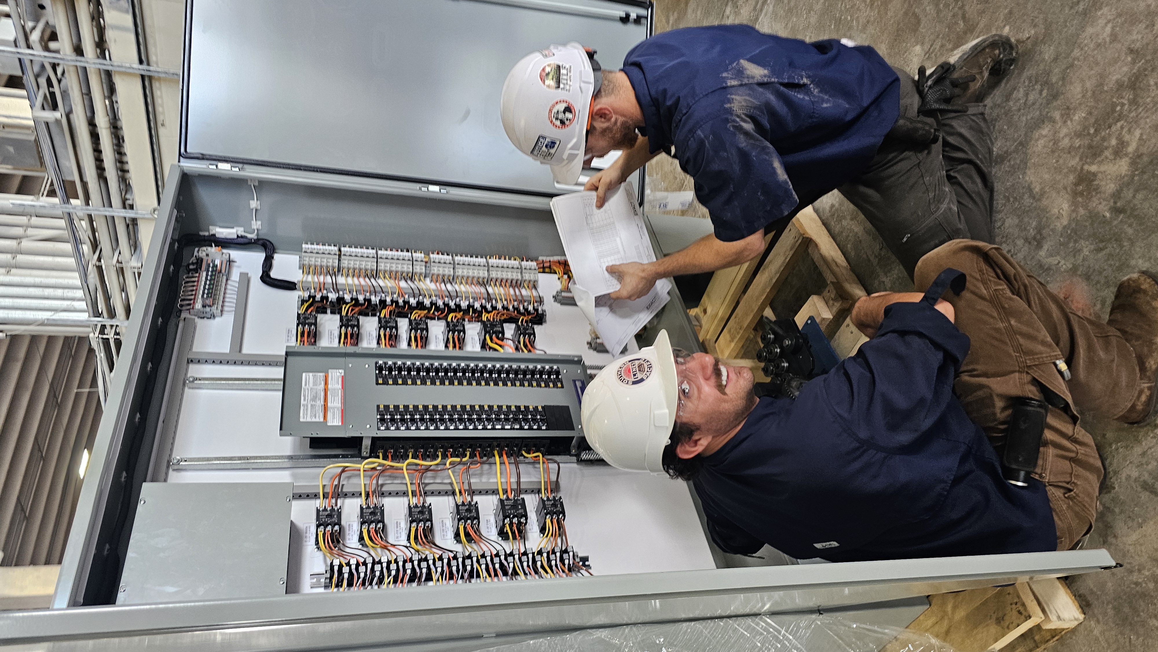 Two licensed electricians working on commercial electrical panel installation in San Antonio